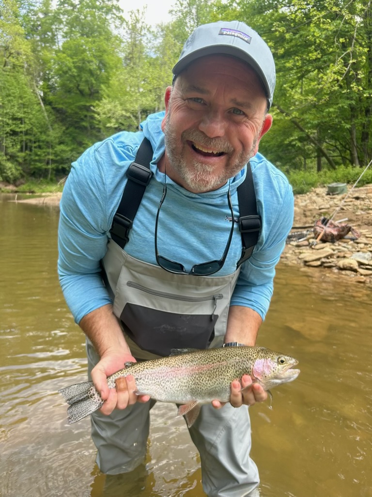 Dan Green holding a trout on a river