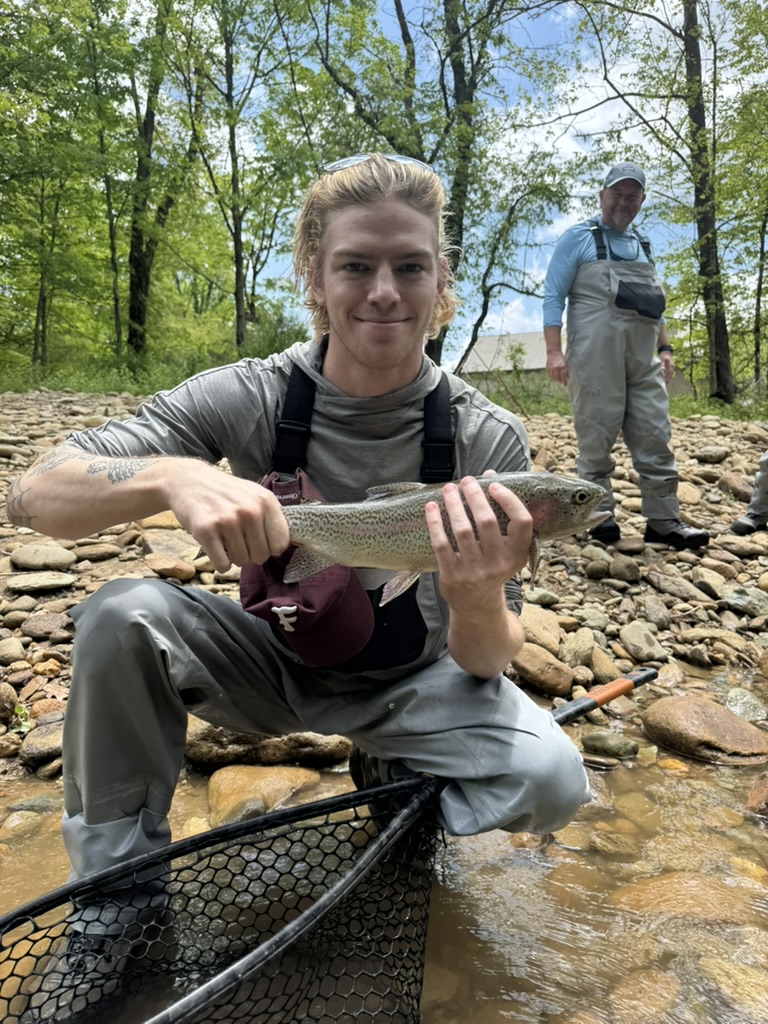 Connor Green kneeling by a river with a fishing net